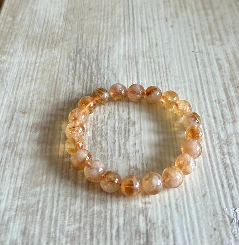 May include: A bracelet made of round, orange and white beads. The beads have a translucent, cloudy appearance.