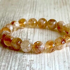 May include: A bracelet made of round, translucent, golden-brown beads with a light brown, cloudy appearance.