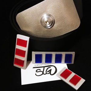 Peut inclure: Trois insignes de grade d'officier de style Star Trek en métal argenté. Une épingle a trois barres rouges, une a quatre barres bleues et une a deux barres rouges. Les épingles sont sur une carte blanche avec le texte "CREATIONS  SLa" en noir.