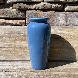 May include: A blue ceramic vase with a smooth, glossy finish. The vase has a rounded base and a slightly flared opening.