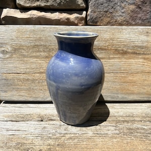 May include: A blue ceramic vase with a crackled glaze. The vase has a rounded body and a narrow neck.