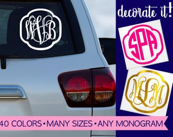 May include: A white vinyl monogram decal applied to a car rear window, with additional hot pink and gold monogram decals shown separately. The text "decorate it!" and "40 COLORS • MANY SIZES • ANY MONOGRAM" appear on the image.
