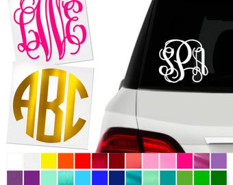 May include: Monogram car decals in pink, gold, and white. The decals feature elegant cursive initials and a circular design. A color chart with various options is shown below the decals.
