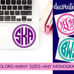 May include: Three circular vinyl decals featuring custom monograms. One purple decal with the letters SKA is on a laptop. A pink decal with letters MLM and a teal decal with letters BWS are shown. Text reads decorate it! 40 COLORS MANY SIZES ANY MONOGRAM.