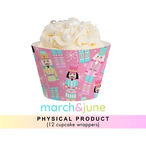 May include: Pink cupcake wrappers with a Nutcracker theme. The wrappers feature a repeating pattern of Nutcracker soldiers in blue, pink, and gold, with snowflakes and a white background. The text "march&june" is printed on the bottom of the wrappers.  PHYSICAL PRODUCT (12 cupcake wrappers)