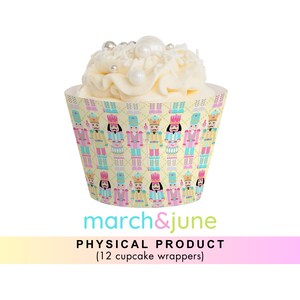 Könnte beinhalten: Ein Set mit 12 Cupcake-Verpackungen mit einem sich wiederholenden Muster von Nussknacker-Soldaten in Rosa, Blau und Gelb auf gelbem Hintergrund. Der Text "march&june" ist unter den Cupcake-Verpackungen gedruckt.