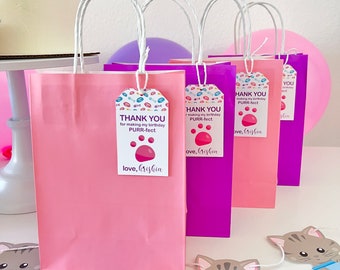 May include: Pink and purple gift bags with white handles and thank you tags that say "Thank you for making my birthday purr-fect." The tags have a paw print and the text "love, Krishia".