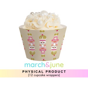 Könnte beinhalten: Ein Set mit 12 Cupcake-Verpackungen mit einem sich wiederholenden Muster aus Nussknacker-Illustrationen. Die Nussknacker tragen rosa und goldene Kostüme und haben weiße Gesichter. Die Verpackungen sind beige mit einem dezenten goldenen Muster.