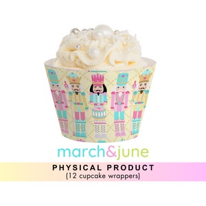 Könnte beinhalten: Ein Set mit 12 Cupcake-Verpackungen mit einem fantasievollen Nussknacker-Motiv. Die Verpackungen sind gelb mit einem rosa, blauen und grünen Muster von Nussknacker-Soldaten. Die Verpackungen sind mit Herzen, Kronen und Sternen verziert.