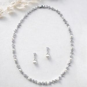 A necklace and earrings are displayed on a white background.