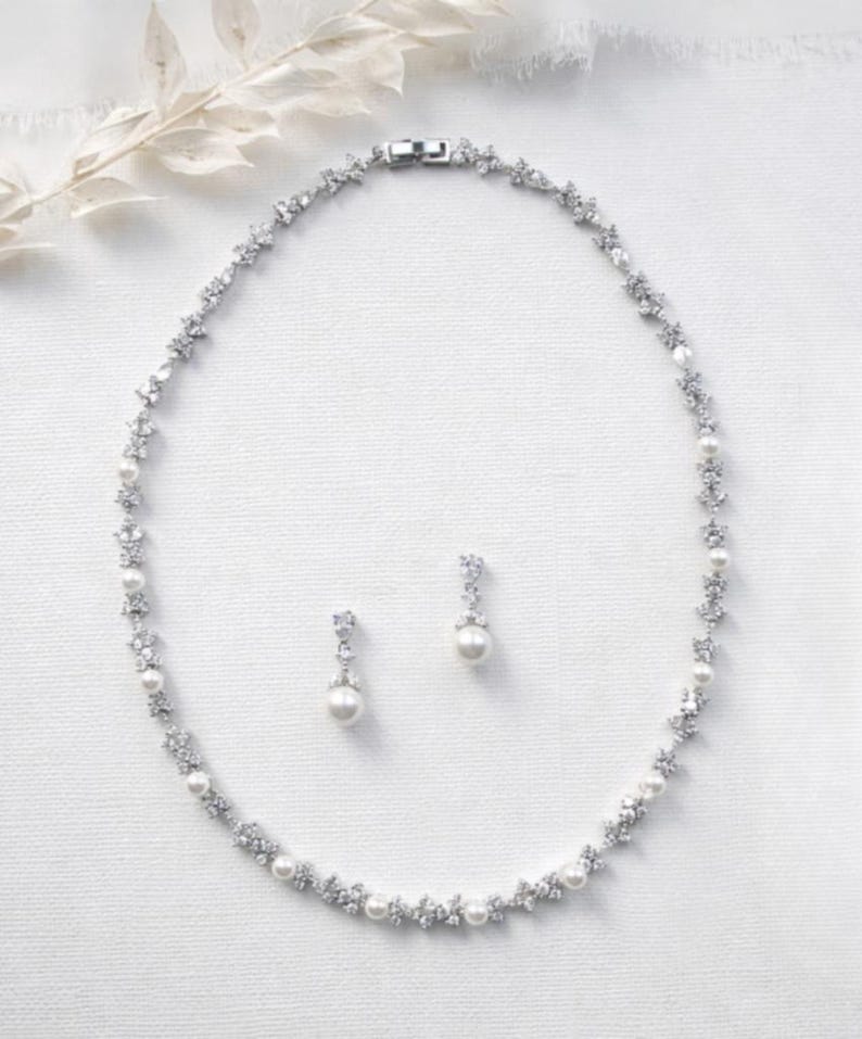A necklace and earrings are displayed on a white background.
