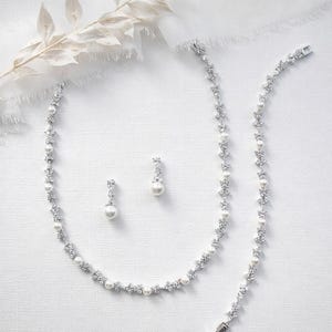 a collection of elegant jewelry pieces, including a necklace, earrings, and a bracelet, all adorned with sparkling diamonds and pearls.