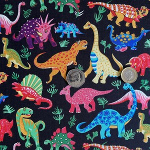 May include: A black fabric featuring a colorful dinosaur pattern. The dinosaurs are in various colors, including red, green, yellow, and blue, with a variety of patterns. The design includes stylized plant life and two coins.
