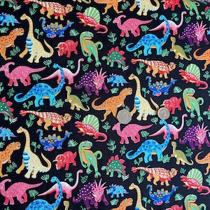 May include: Black fabric with a colorful dinosaur pattern. The dinosaurs are in various colors, including orange, blue, pink, and green, with some having patterned designs. The background is black, and there are small green plant-like shapes scattered throughout.