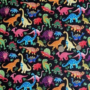 May include: A black fabric covered with colorful cartoon dinosaurs in various poses. The dinosaurs are in shades of red, orange, blue, green, and purple. Small green plant-like shapes are scattered throughout the design.