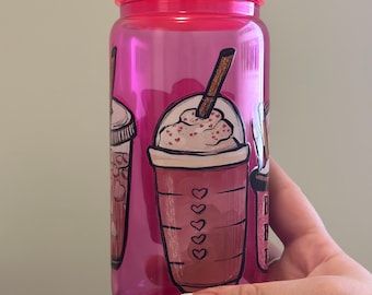 Op de afbeelding: Roze herbruikbare waterfles met een transparant kunststof lichaam en een roze deksel. De fles heeft een afbeelding van drie verschillende koffiedrankjes met slagroom en rietjes.