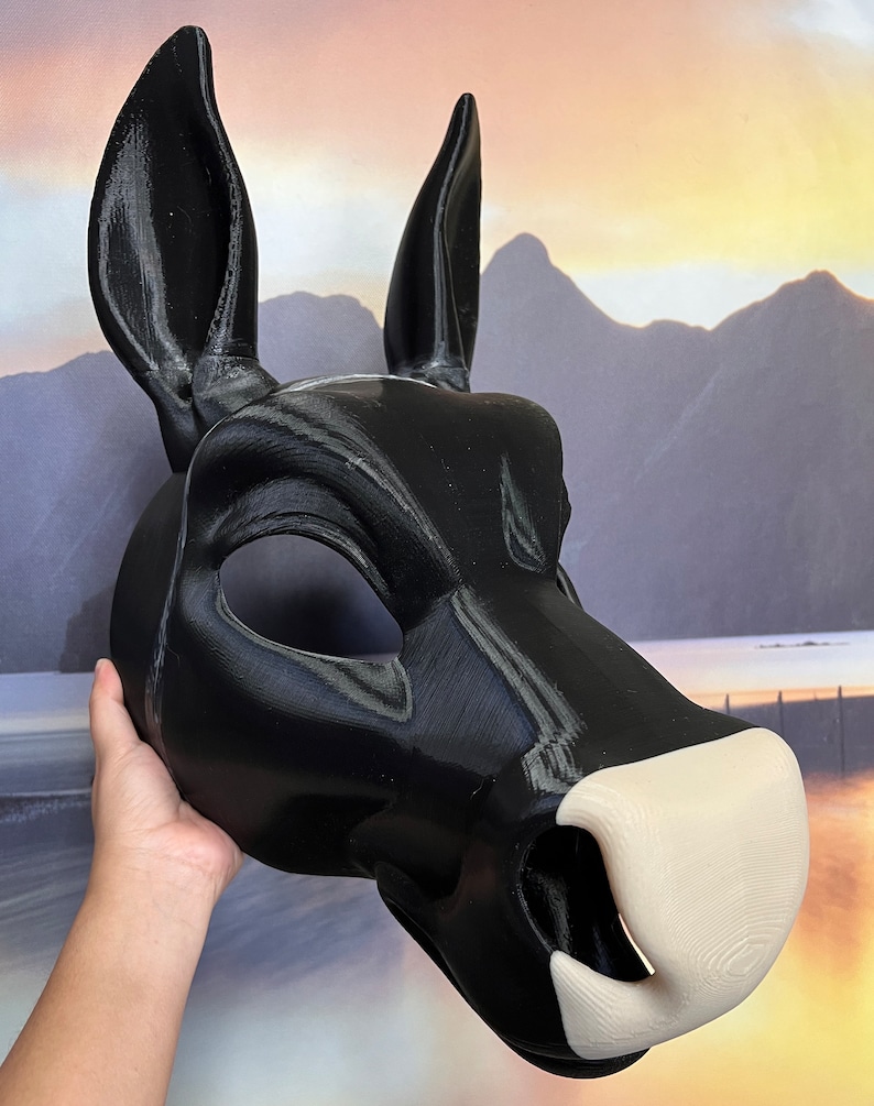 May include: A black and white 3D printed animal mask with large ears. The mask has a detailed snout and a white nose.