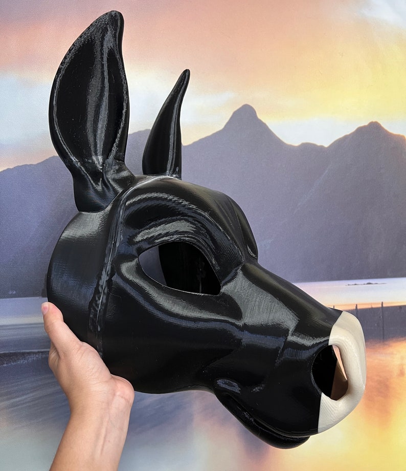 May include: A black furry mask with a white nose and large ears. The mask is made of a smooth, shiny material.