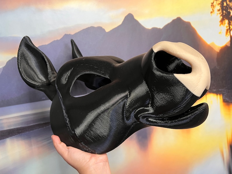 May include: A black and white animal mask with a large, rounded nose and large ears. The mask is made of a smooth, hard material and has a realistic appearance.