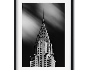 Puede incluir: Una fotografía en blanco y negro del edificio Chrysler en la ciudad de Nueva York. El edificio es alto y estrecho, con una aguja puntiaguda en la parte superior. Las nubes en el cielo están borrosas, creando una sensación de movimiento.