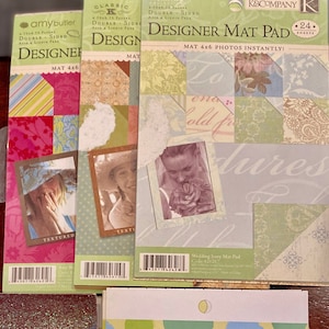 May include: A set of four 4x6 inch designer mat pads with different patterns and colors. The pads are labeled "Classic", "Wedding Ivory", "Textured", and "Amy Butler". Each pad has 24 sheets.