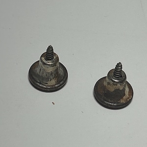 May include: Two antique silver-toned cabinet knobs with a screw on top. The knobs have a slightly worn, aged look.