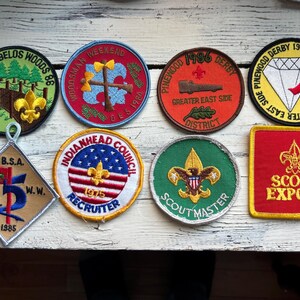 May include: A collection of eight embroidered scout patches. The patches are various colors and feature different designs, including a diamond, a flag, and a scout emblem. The patches are all in good condition and would be a great addition to any scout collection.