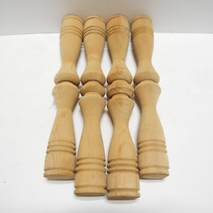 May include: Five unfinished wooden spindles with a turned design. The spindles are approximately 6 inches long and have a diameter of 1 inch.