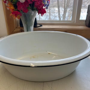 May include: A white ceramic mug with a black handle and the text "But First, Coffee" in a black, handwritten-style font. The mug is on a white surface.