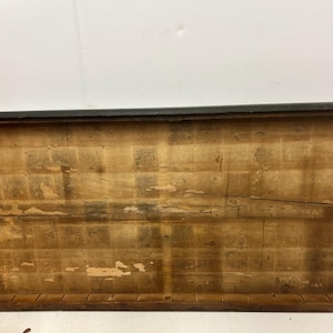 May include: Rectangular wooden frame with a dark brown border. The interior features a light brown, aged wood surface with visible grain and a prominent horizontal crack. The frame's construction is evident, with visible joints and a rustic aesthetic.