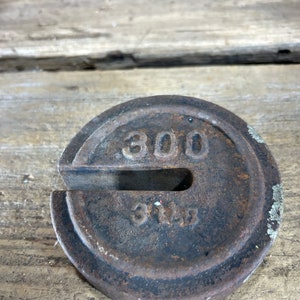May include: A rusty cast iron weight with a 300 pound weight designation. The weight has a U-shaped cutout.