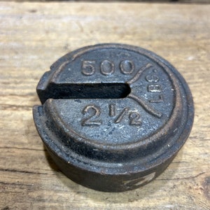 May include: A cast iron weight with the text "500 LBS 2 1/2" embossed on the surface.