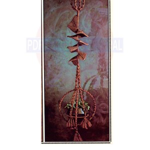 May include: A macrame plant hanger with a brown cord and a spiral design. The hanger is holding a small potted plant. The text "Pagoda" is at the top of the image. The fascination of the orient - caught in one of the most interesting macrame designs ever.