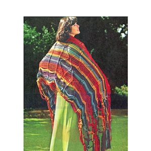 May include: A vibrant, hand-knitted shawl with a geometric design. The shawl displays a spectrum of colours, including red, blue, yellow, and green. The shawl is draped over the shoulders, creating a striking visual effect. The garment is a unique and eye-catching accessory.