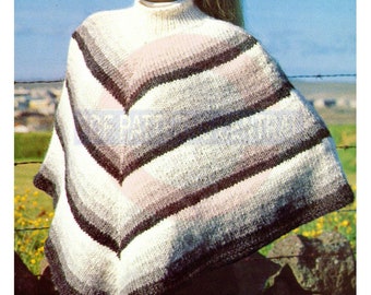 Op de afbeelding: Een gebreide poncho met witte, grijze en roze strepen en een rolkraag. De poncho wordt gedragen door een vrouw met blond haar dat in een paardenstaart is geknoopt. Ze staat voor een hek en een veld met groen gras.