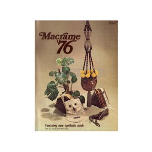 May include: A vintage book cover for a macrame craft book from 1976. The cover features a brown macrame plant hanger with yellow flowers and a white crocheted owl. The title of the book is "Macrame '76" and the text "Featuring new synthetic cords" is below the image.