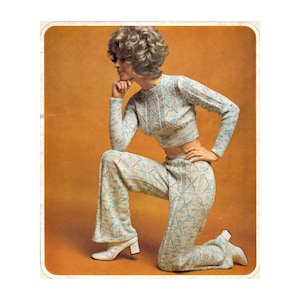 Peut inclure: Un ensemble deux pièces tricoté de style vintage en bleu clair, blanc et marron. L'ensemble comprend un pull à manches longues court et un pantalon évasé. Le modèle porte des bottines à talons blanches. Le fond est de couleur orange uni.