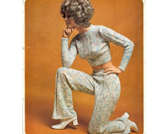 May include: A retro knitted two-piece outfit in light blue, white, and brown. The set comprises a cropped long-sleeved sweater and flared trousers. The model is wearing white heeled boots. The background is a solid orange colour.