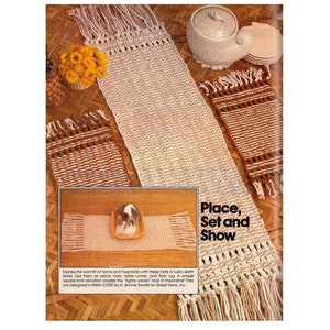 May include: A set of three macrame mats in earth tones. The mats are made with a simple square-knot variation and have fringe edges. The mats are shown on a wooden surface with a ceramic bowl and plates. The text "Place, Set and Show" is printed on the page.