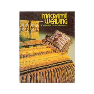 Puede incluir: Un libro titulado "Macrame Weaving: A Marriage of the Fiber Arts" con una alfombra de macramé amarilla y marrón y una almohada en la portada.