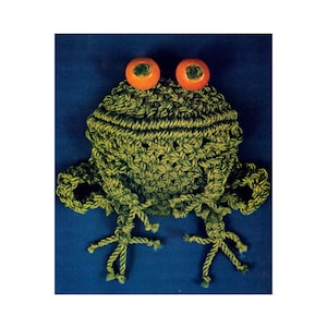May include: Green crocheted frog with orange eyes. The frog has a textured surface and is made of rope.
