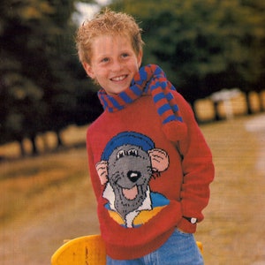 Puede incluir: Un suéter de punto rojo con un diseño de ratón de dibujos animados. El suéter tiene una bufanda a rayas azul y roja alrededor del cuello.