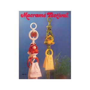 May include: A vintage macrame pattern booklet featuring two frog-themed towel holders. The holders are made with white and green yarn and feature a frog figurine at the top. The booklet cover has the text "Macrame Festival!" in red letters.