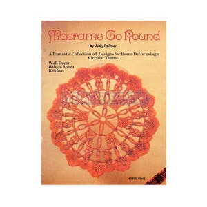 May include: A macrame wall hanging with a circular design in shades of orange and brown. The design is called "Macrame Go Round" and is by Judy Palmer. The text "#7430, Plaid" is in the bottom right corner of the image.