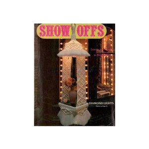 Könnte beinhalten: Ein Magazin-Cover mit einer Makramee-Lampe mit dem Titel "SHOW OFFS" und dem Text "Lamps of the Future, New Ideas in Macrame". Der Lampenschirm ist weiß und hat ein Diamantenmuster. Das Magazin-Cover enthält auch den Text "DIAMOND LIGHTS Pattern on Page 13."