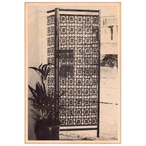 May include: A black crocheted room divider with a geometric pattern. The divider is made of thick yarn and has a wooden frame.
