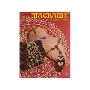 Könnte beinhalten: Buchcover mit dem Titel "How to Macrame' With Small Cords". Das Cover zeigt eine Nahaufnahme eines Makramee-Stücks mit Perlen und einer Feder.