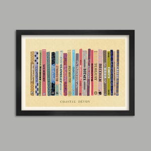 Puede incluir: Impresión enmarcada que muestra una fila de lomos de libros coloridos, cada uno con el nombre de una ciudad costera de Devon. El texto "Coastal Devon" está en la parte inferior. Los libros están sobre un fondo amarillo claro.