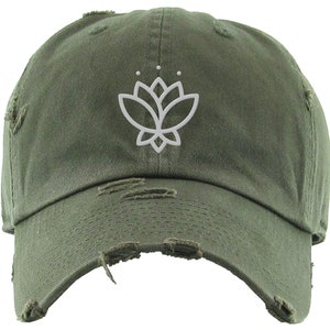 May include: A green distressed baseball cap with a white outline of a lotus flower on the front.