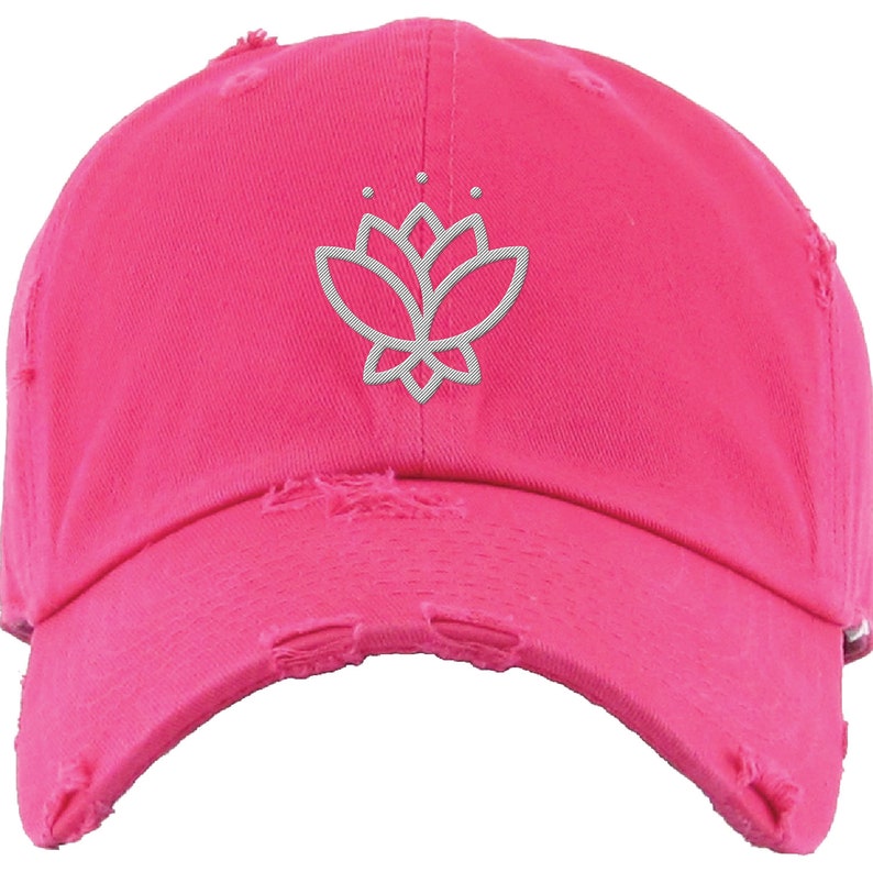 May include: A pink distressed baseball cap with a white embroidered lotus flower design.